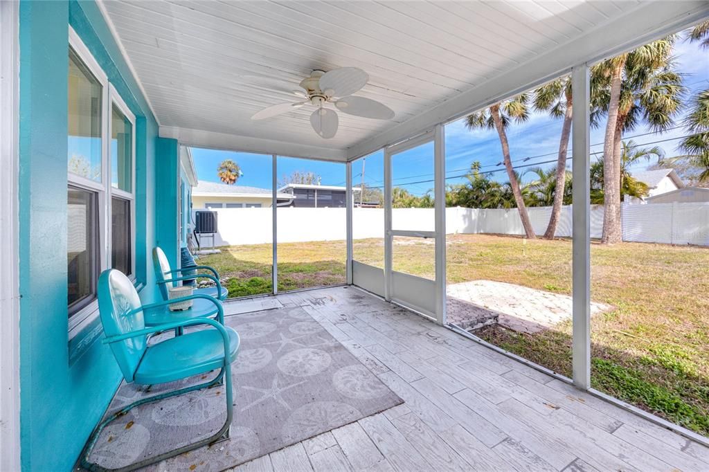 Covered back porch with tile flooring looking out to the large back yard.