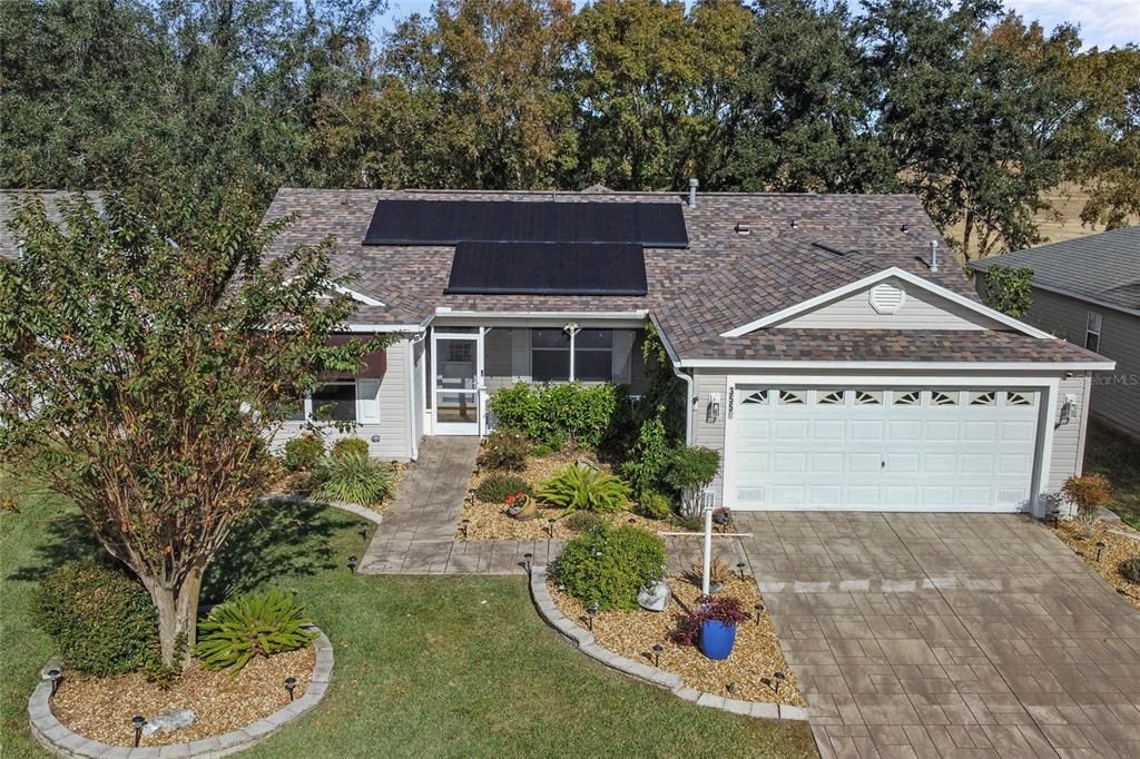 Exterior Front showcasing stamped driveway, solar panels and lush landscaping