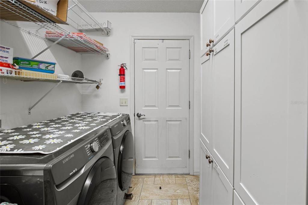 Pass through laundry room from garage with cabinets to one side used as a pantry