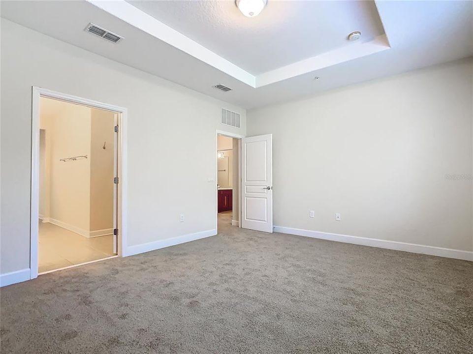 Another view of the primary bedroom looking toward the ensuite bathroom and the hallway to the other bedrooms.