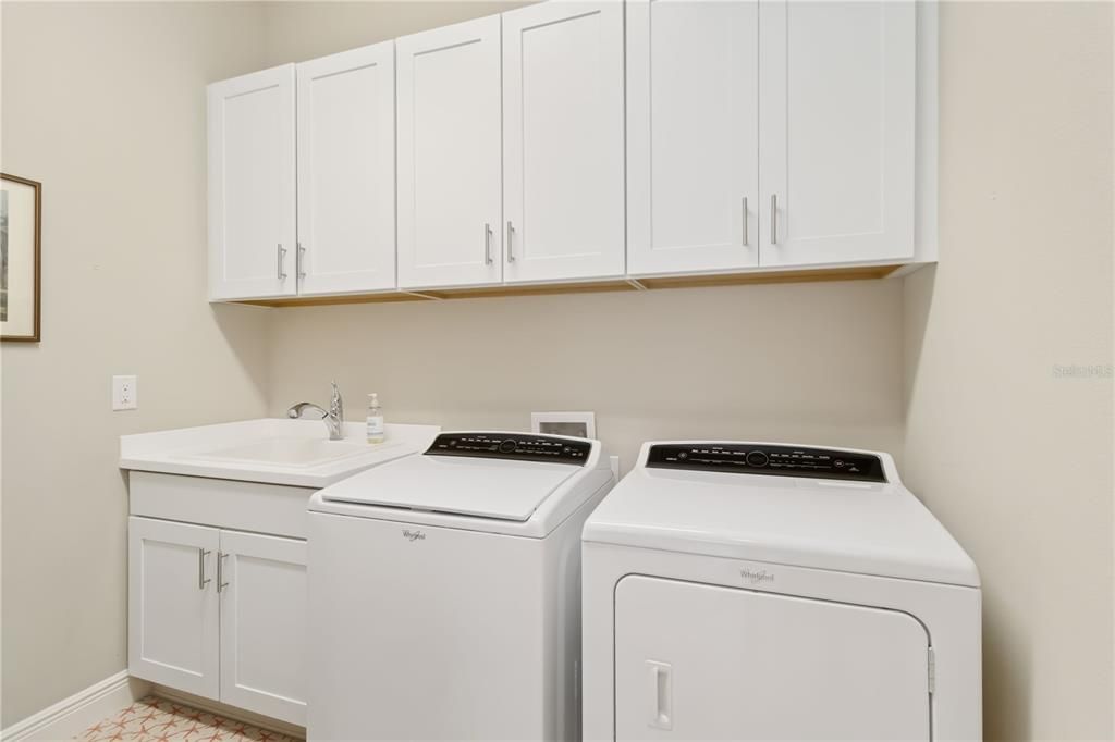 Inside laundry has sink, washer/dryer and cabinetry for storage