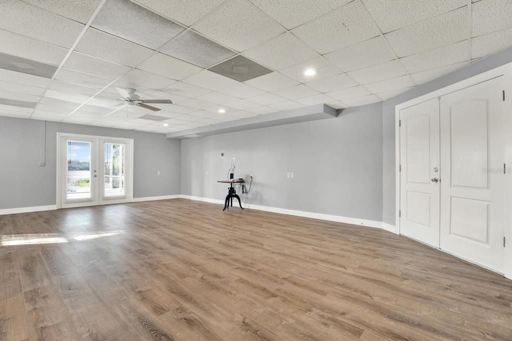 Downstairs bonus room with new LVP and paint!  Double doors on left lead to covered lanai and pool! Double doors on the right lead to tandem three car garage