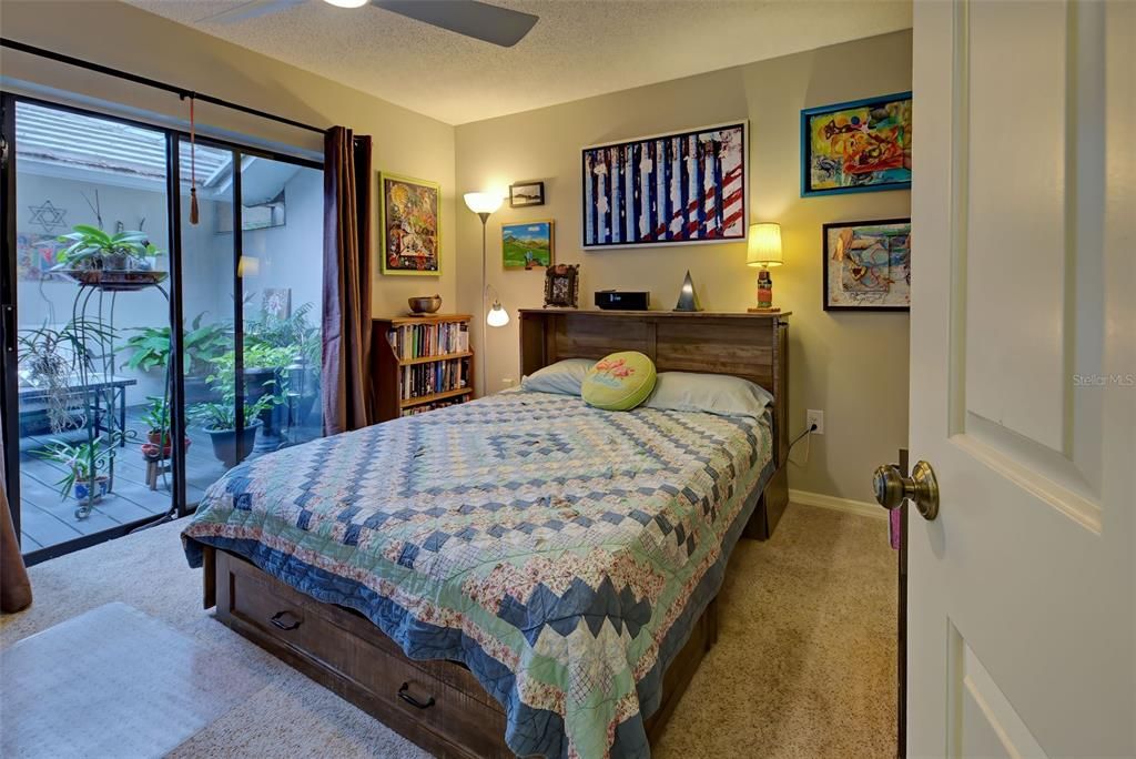 The guest bedroom has sliding glass doors opening to the deck area.