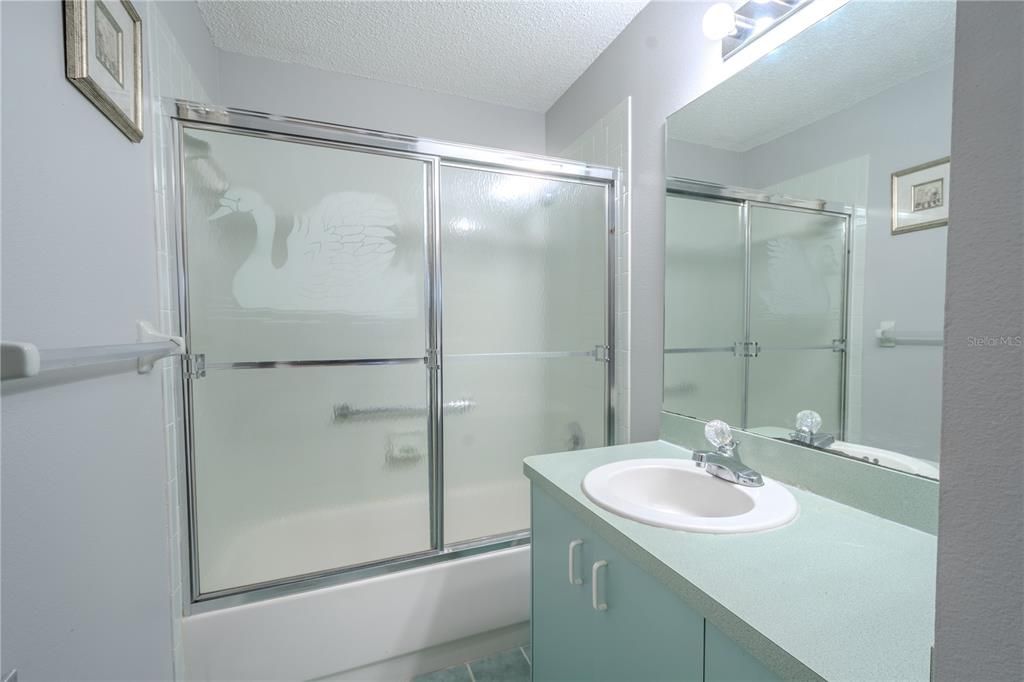 The 2nd bathroom feature a mirrored vanity with storage, ceramic tile floor and a tub with shower.