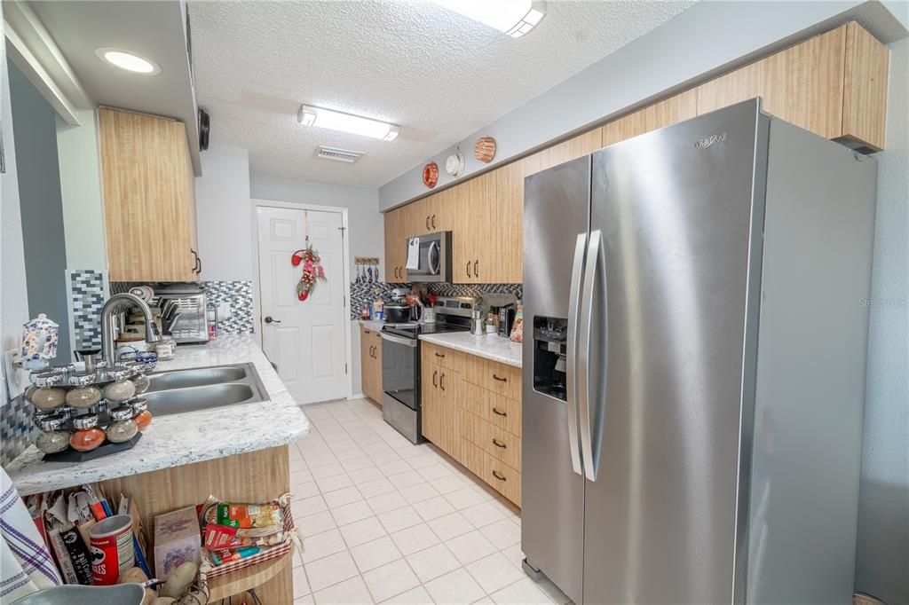 The kitchen features a suite of stainless steel appliances including a French door refrigerator with water dispenser and ice maker, a range/oven, a microwave and dishwasher.