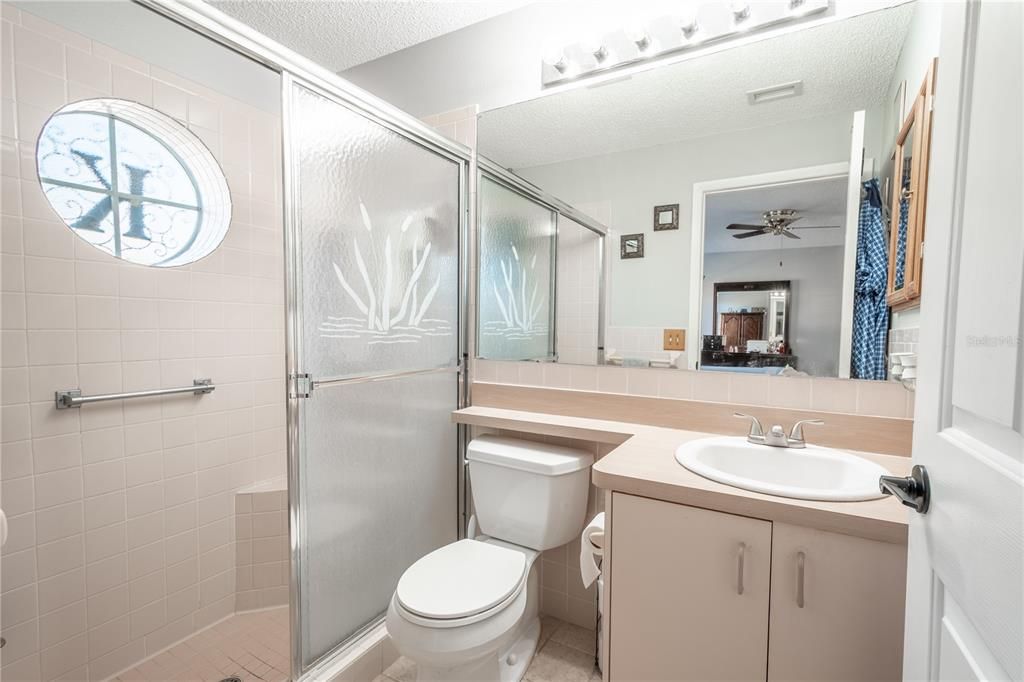 The primary ensuite bath features a mirrored vanity with storage, and a walk in shower with built in bench and ceramic tile floor.