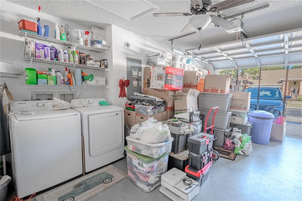 The garage features a washer and dryer with shelving, a ceiling fan with light kit, a screen door and electric door opener.