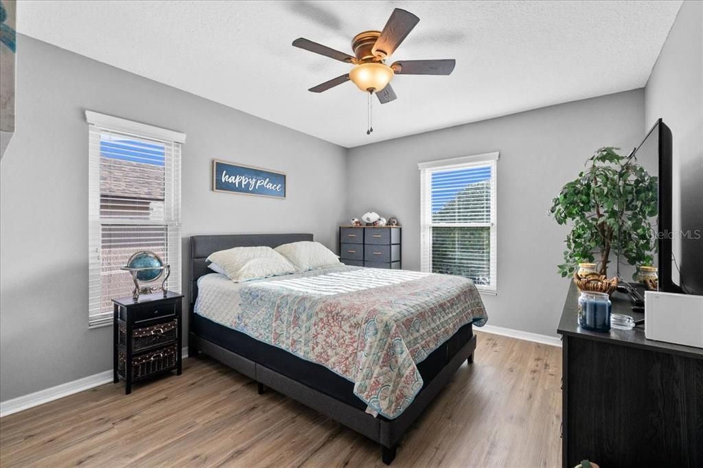 This is the Second Bedroom, with a garden view both Northward + Eastward, luxury vinyl plank woodgrain flooring, a ceiling fan/light, and a built-in closet.