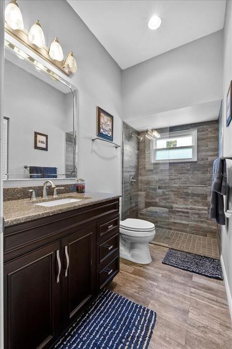 The Second Bath - wow! A walk-in shower with ceramic tile flowing from the floor all the way into the shower, sleek glass partition, a high shower window, updated cabinets + countertops, and high ceilings.