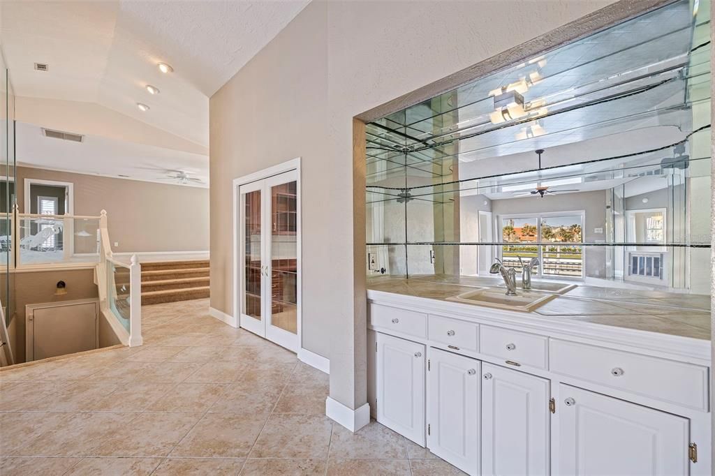 View of wet bar, den/office/guest room with and stairs leading down to 3-car garage and storage areas