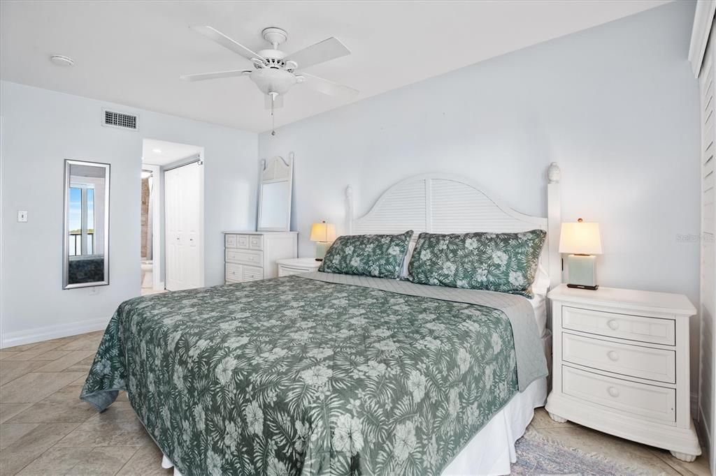 Primary bedroom with king size bed, views of Tampa Bay, and patio access.