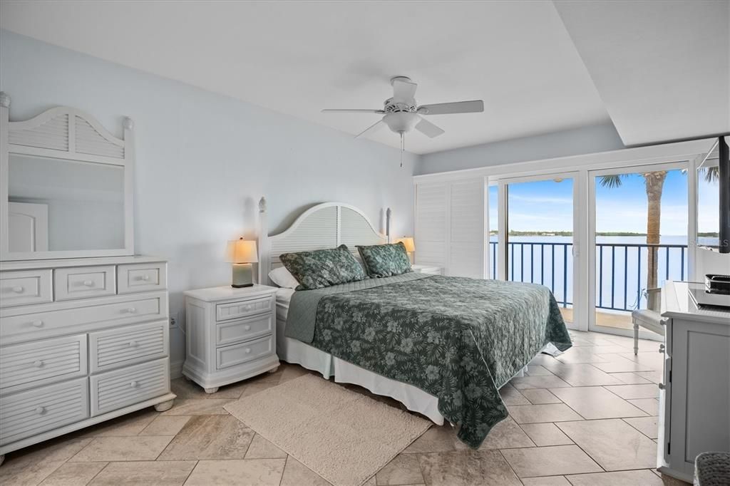 Primary bedroom with king size bed, views of Tampa Bay, and patio access.