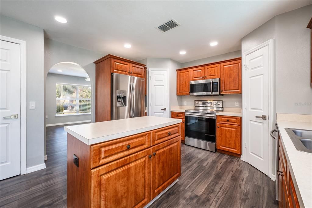 hrough arched doorways your modern kitchen awaits, comfortable for the home chef with not one but TWO PANTRIES for ample storage, a great mix of cabinet and drawer storage, STAINLESS STEEL APPLIANCES, a prep ISLAND and a casual dining space in front of sliding glass doors for a view of the pool.