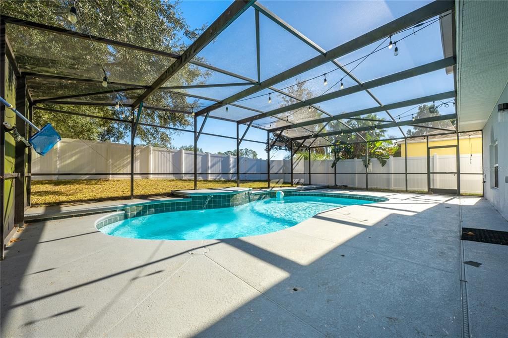 SCREENED POOL OVERLOOKS A FENCED YARD.