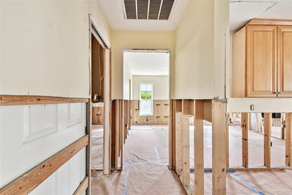 Hallway off the kitchen.  Laundry room and garage entrance is to the left and the primary suite is beyond that.  The bedroom faces the pool and canal.  To the left is a large walk in closet and a primary bathroom.