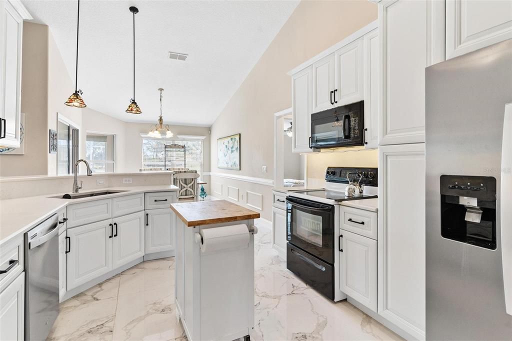 Remodeled kitchen features new cabinets, quartz countertops, soft close drawers, and porcelain tile.