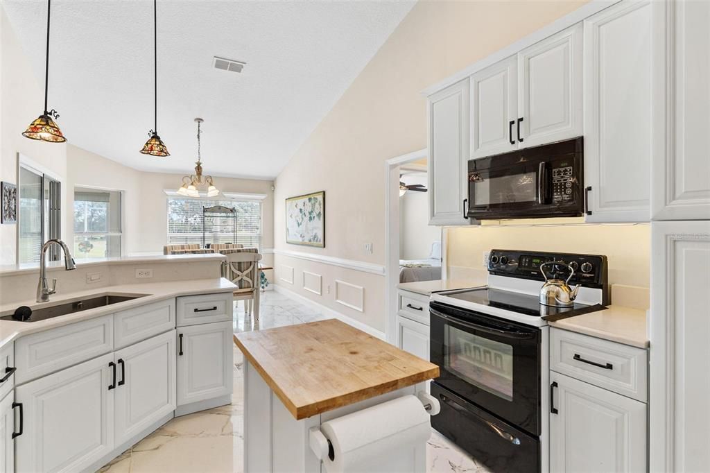 Remodeled kitchen features new cabinets, quartz countertops, soft close drawers, and porcelain tile.