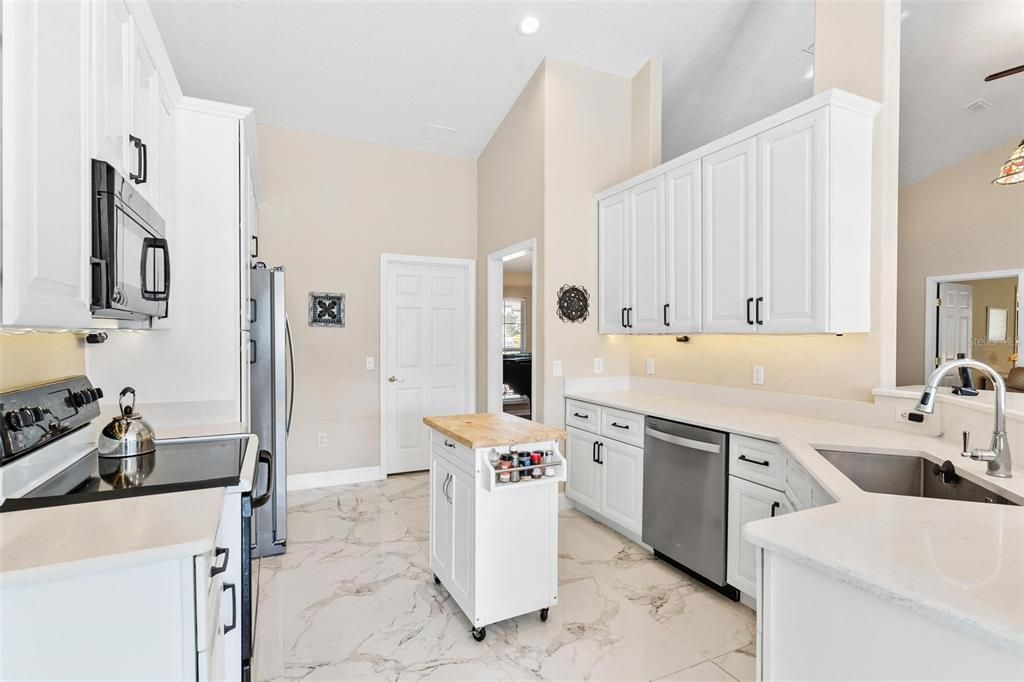 Remodeled kitchen features new cabinets, quartz countertops, soft close drawers, and porcelain tile.