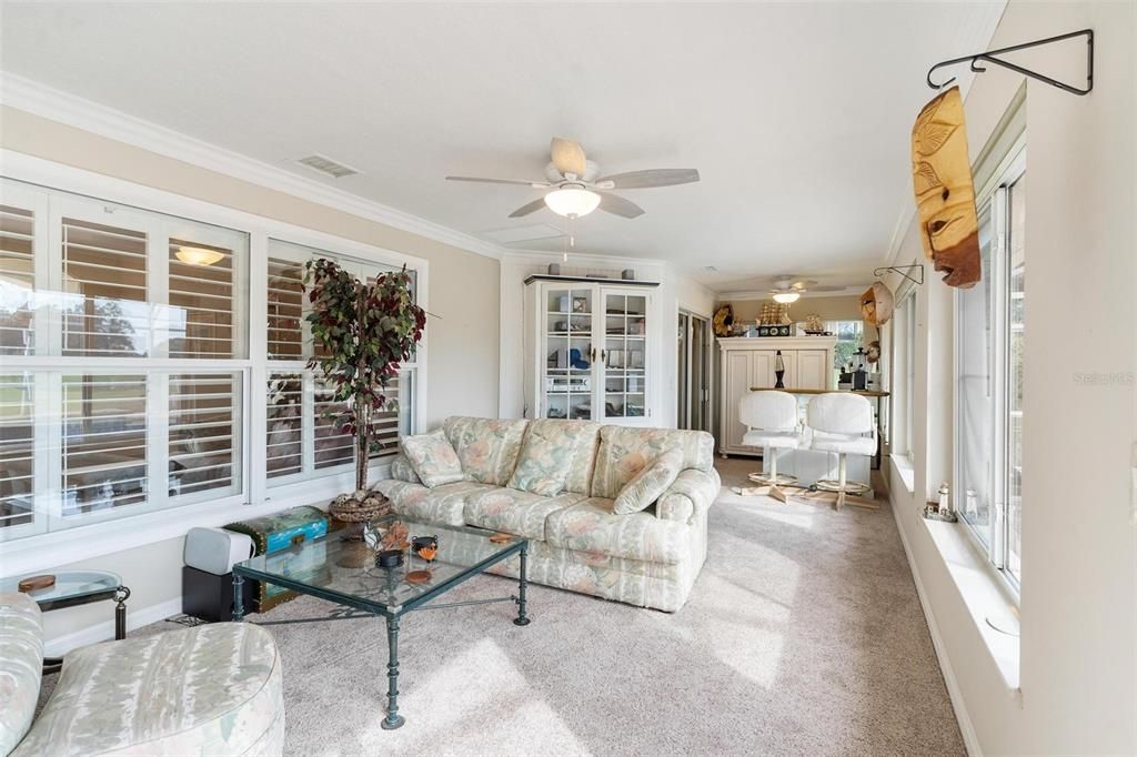 Florida room overlooks swimming pool with views of golf course.