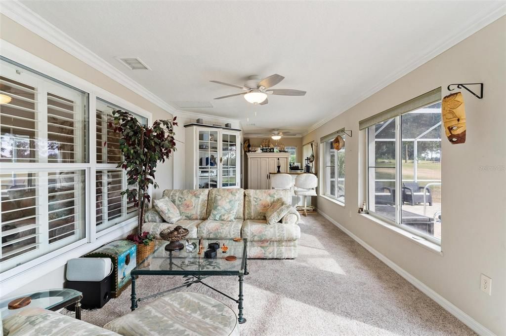 Florida room overlooks swimming pool with views of golf course.