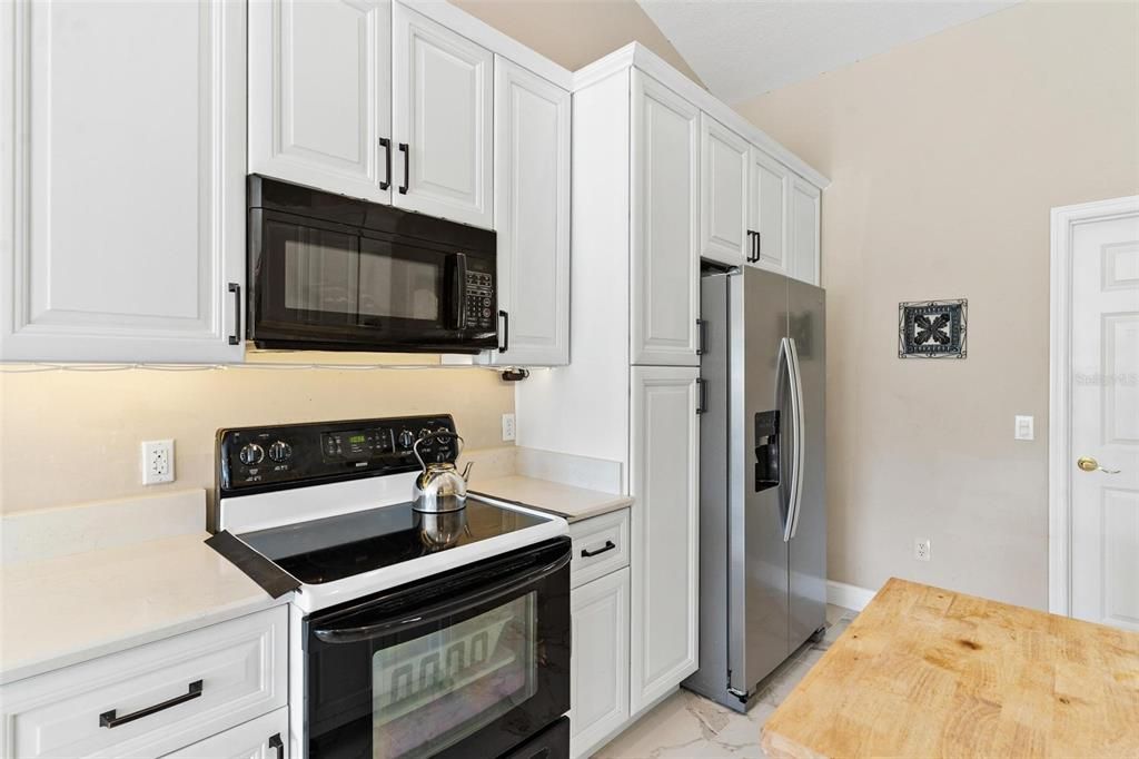 Remodeled kitchen features new cabinets, quartz countertops, soft close drawers, and porcelain tile.