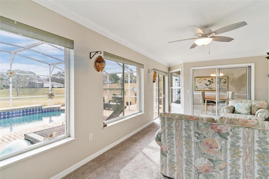 Florida room overlooks swimming pool with views of golf course.