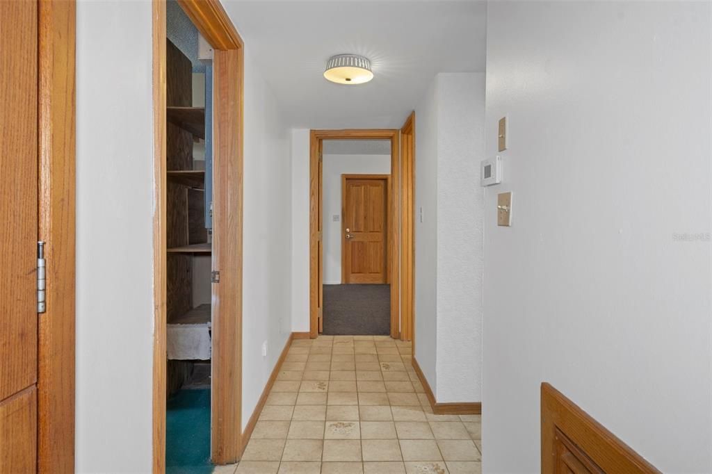 hallway from bonus room to kitchen with utility door on left and laundry on right