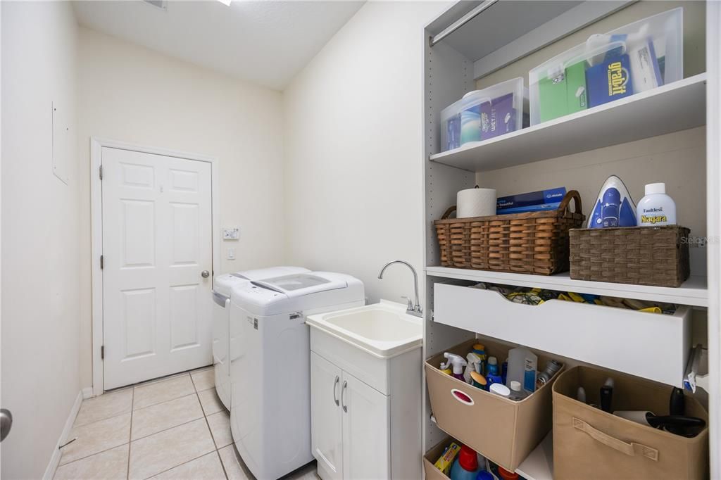 Utility room with sink, ample storage and entrance to garage