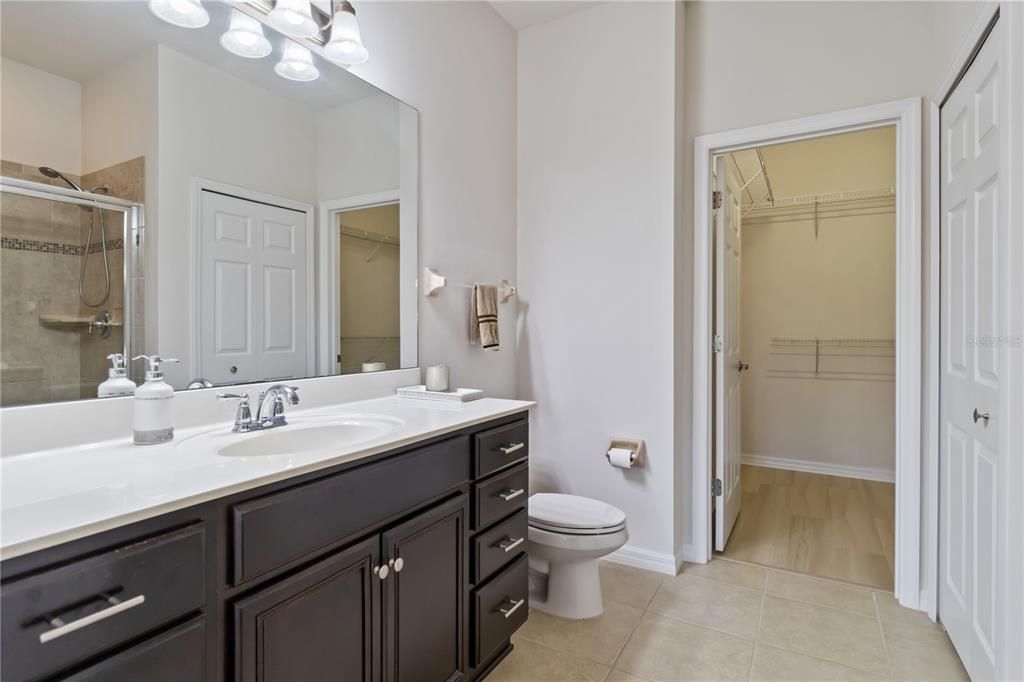 Primary bathroom equipped with oversized granite countertop, walk in closet, linen closet and walk in shower.