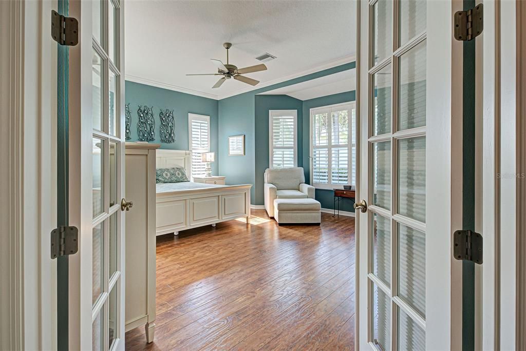 Double doors to the sumptuous primary suite, painted in soothing beachy colors.