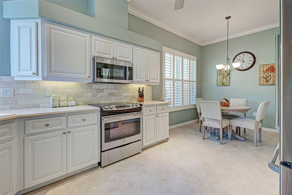 Kitchen has new cabinets with pull-out drawers, beautiful backsplash and cheerful breakfast nook.