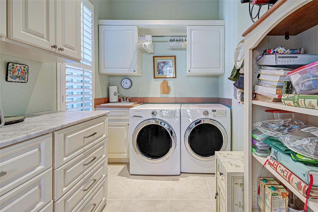 Large, interior laundry room with has storage galore and tub.