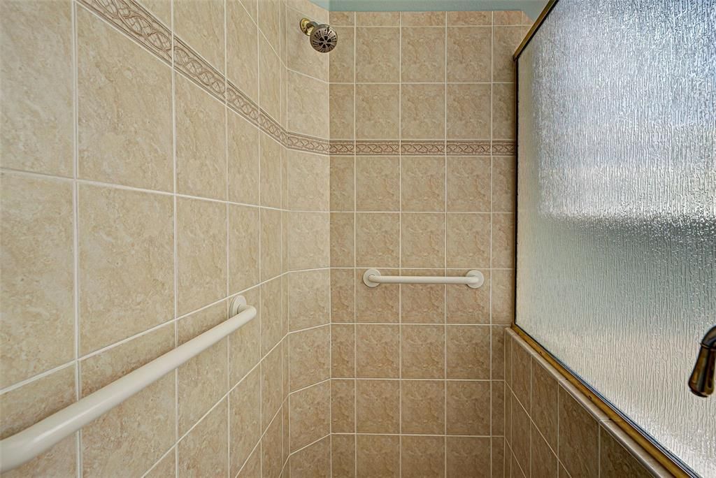 Primary bathroom tiled, walk in shower with handholds.