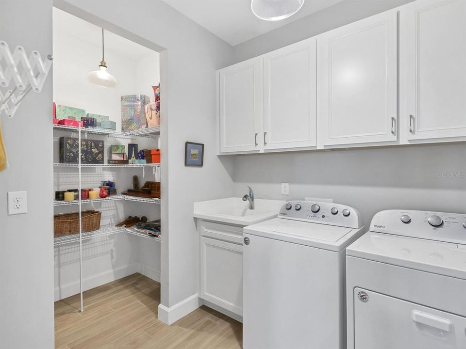 Laundry room with updated lighting and extra storage room, cabinets, sink