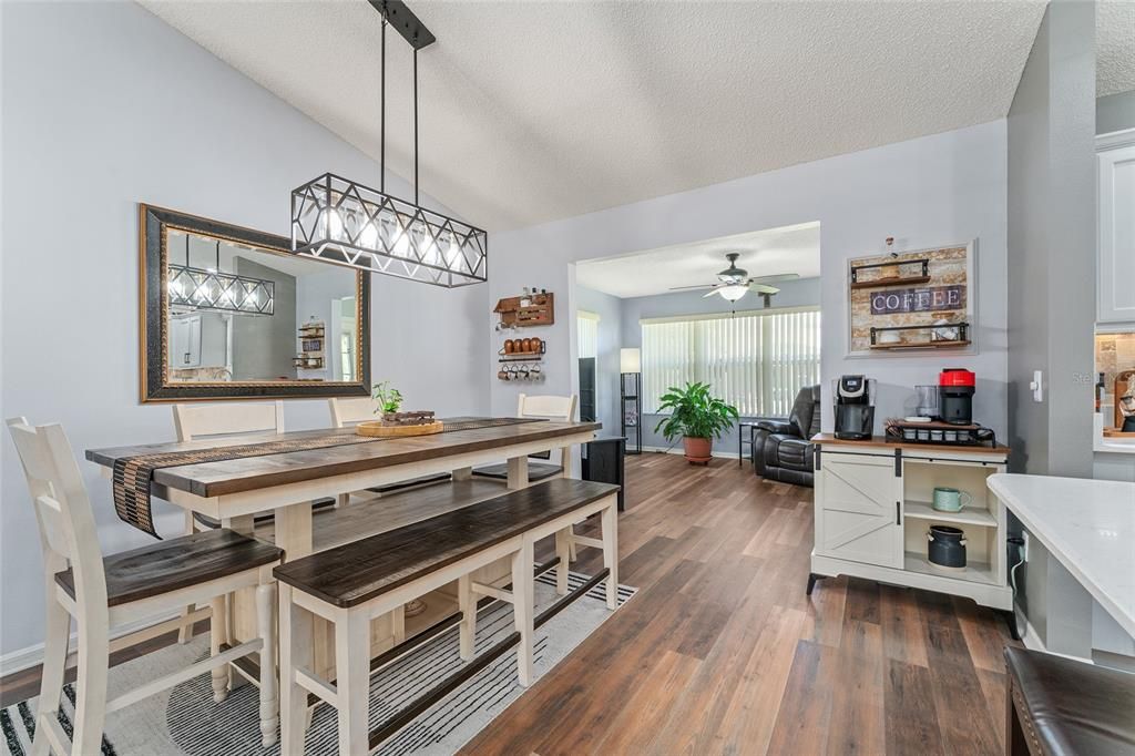 DINING ROOM - Note BAR HEIGHT dining table set with gorgeous farmhouse style chandelier overhead. FLORIDA ROOM is visible in back center.