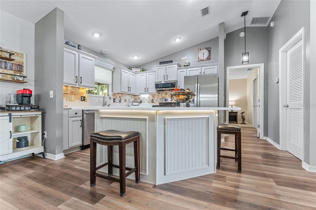 Another view of KITCHEN features unique underlighting of QUARTZ COUNTERTOP of ISLAND and beadboard & woodworking panels on front.