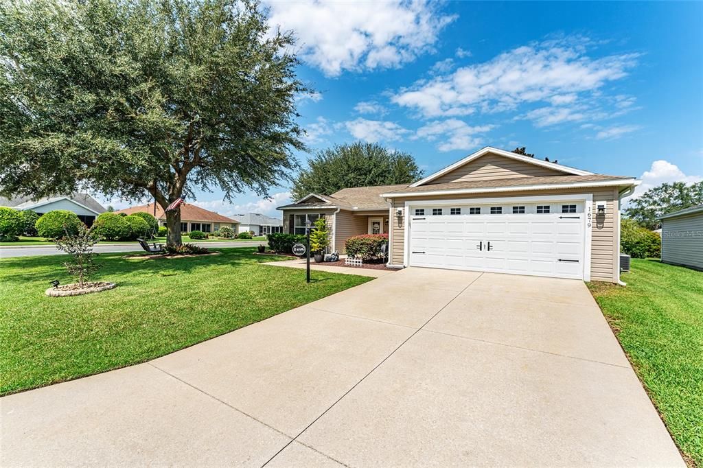 FRONT EXTERIOR shows CORNER LOT with large OAK TREE & charming WOODEN SWING in front yard.