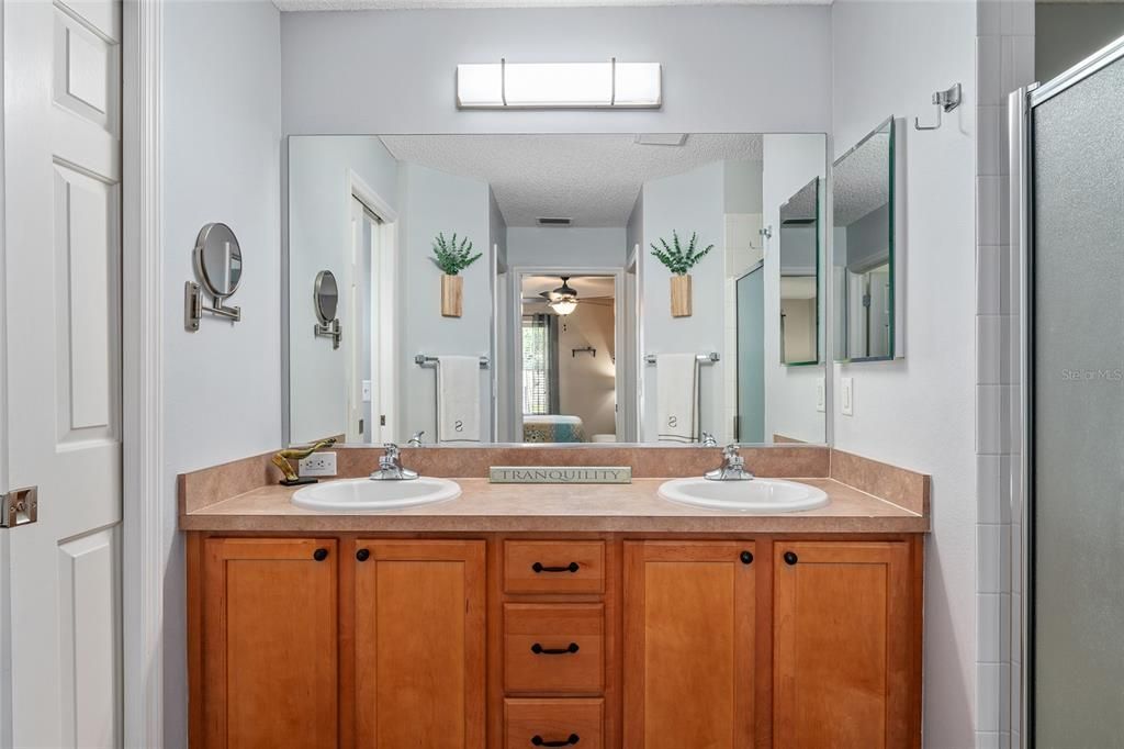 Another view of PRIMARY ENSUITE  BATHROOM shows dual sinks/vanity & updated lighting fixture. Note POCKET DOOR on L to private water closet and WALK-IN shower on R.