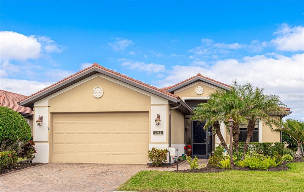 Beautiful paver driveway and walkway with new tropical landscaping leading to an enclosed front porch.