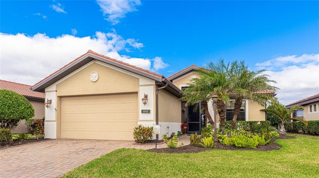 Beautiful paver driveway and walkway with new tropical landscaping leading to an enclosed front porch.