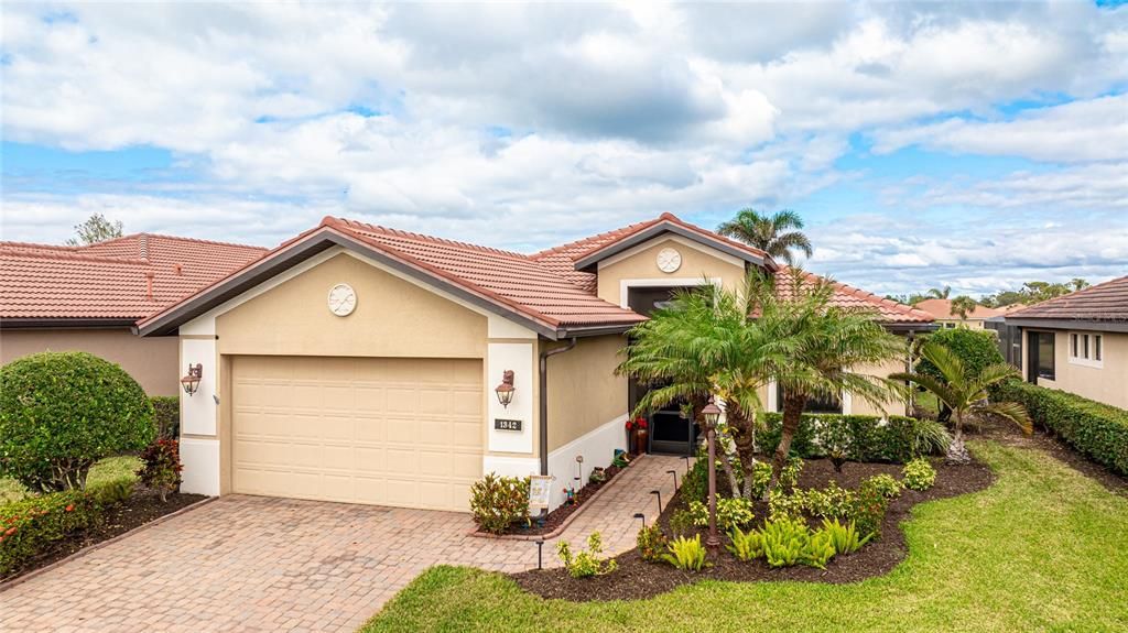 Beautiful paver driveway and walkway with new tropical landscaping leading to an enclosed front porch.