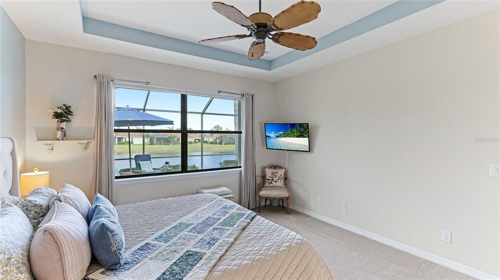 Primary bedroom overlooking the Lanai with pool and water view and with ensuite primary bathroom.