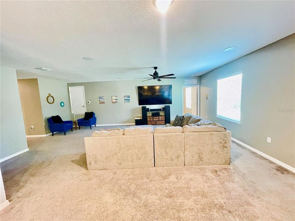 Impressive size TV Room with ceiling fan, view of backyard and plenty of space to host a family gathering.