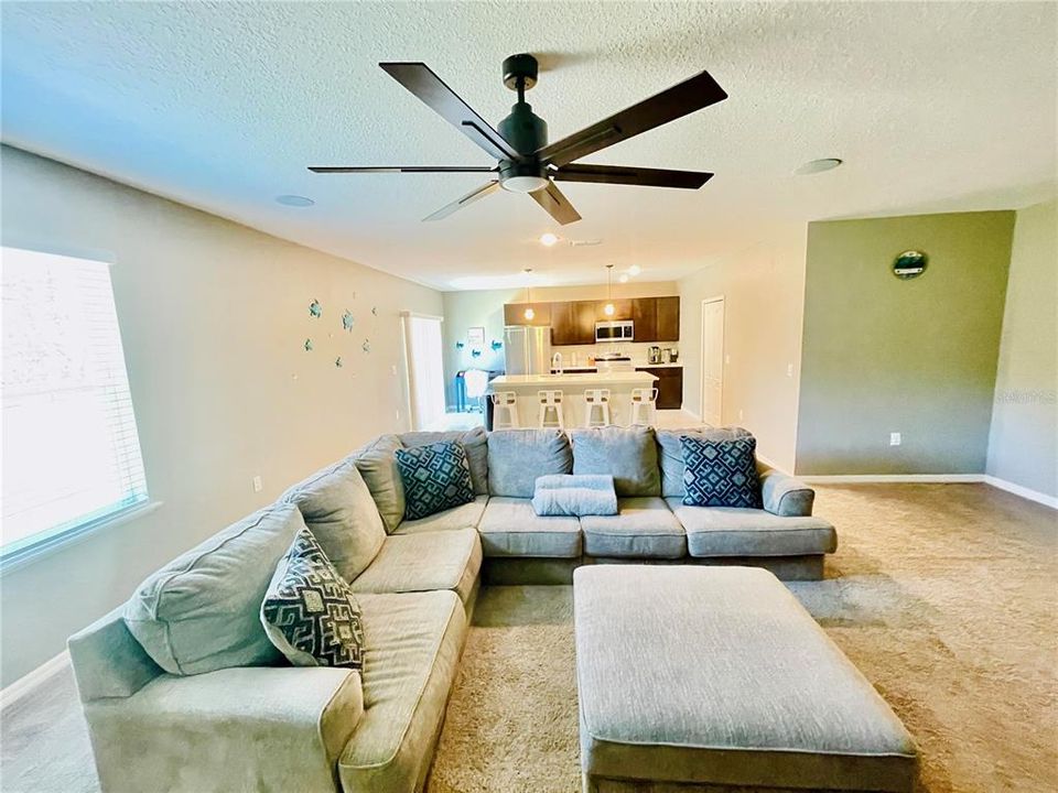 Impressive size TV Room with ceiling fan, view of backyard and plenty of space to host a family gathering.