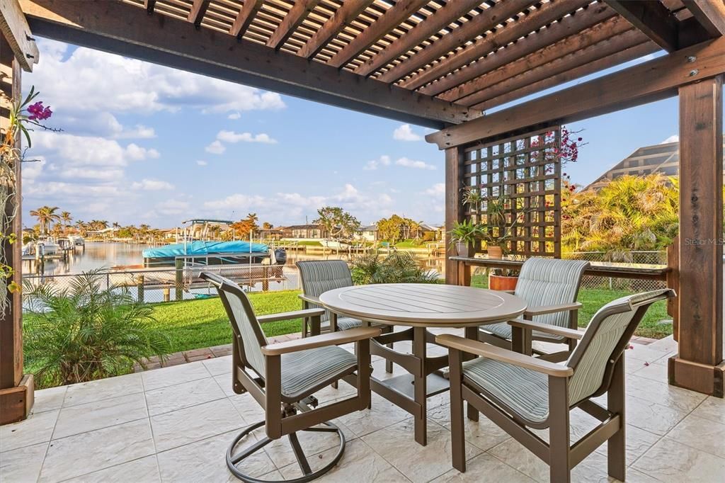 Pergola-covered outdoor dining area with adjoining outdoor Kitchen and sitting area