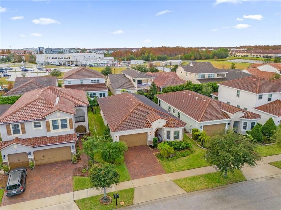 A beautiful Mediterranean-style home featuring elegant clay roof tiles, a stylish arched entryway, and a paved driveway. The landscaping completes this stunning curb appeal in the Eagle Creek Community of Lake Nona.