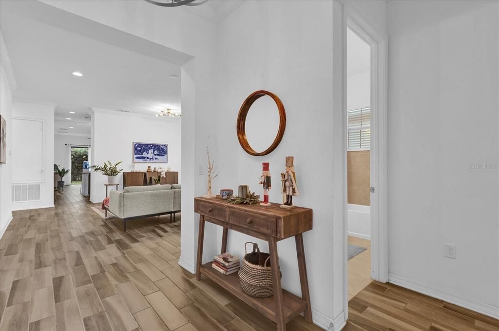 Step into this bright and inviting living room, featuring elegant wood-look tile flooring, large windows that let in ample natural light, and a modern light fixture that adds a touch of sophistication. The open layout offers a perfect blend of comfort and style, making it ideal for entertaining or relaxing with family.