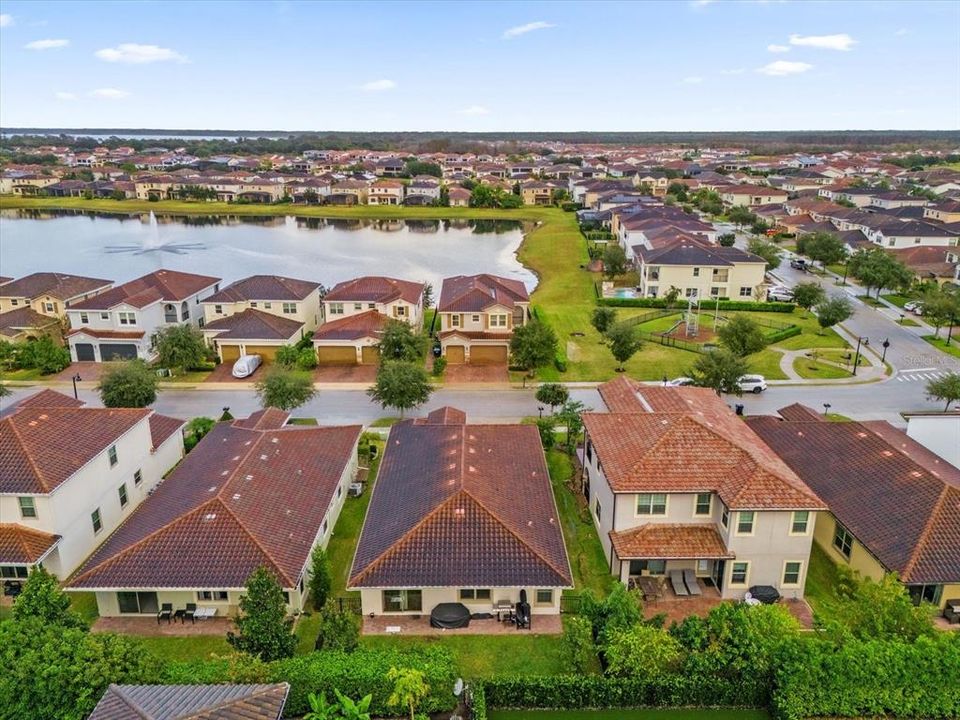 A beautiful Mediterranean-style home featuring elegant clay roof tiles, a stylish arched entryway, and a paved driveway. The landscaping completes this stunning curb appeal in the Eagle Creek Community of Lake Nona.