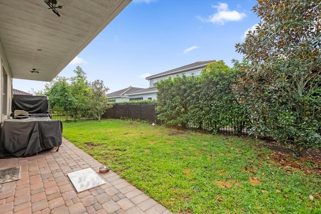 Spacious backyard featuring a covered patio, paved flooring and outdoor lights perfect for outdoor entertaining or relaxing. The fenced yard offers security, ideal for families or pets to enjoy.