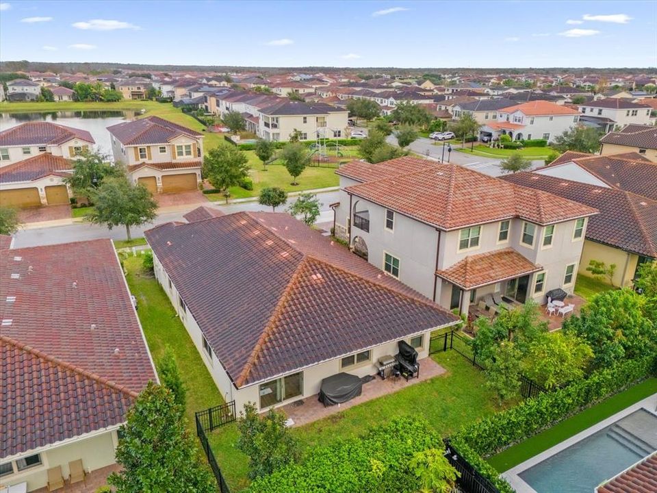 A beautiful Mediterranean-style home featuring elegant clay roof tiles, a stylish arched entryway, and a paved driveway. The landscaping completes this stunning curb appeal in the Eagle Creek Community of Lake Nona.